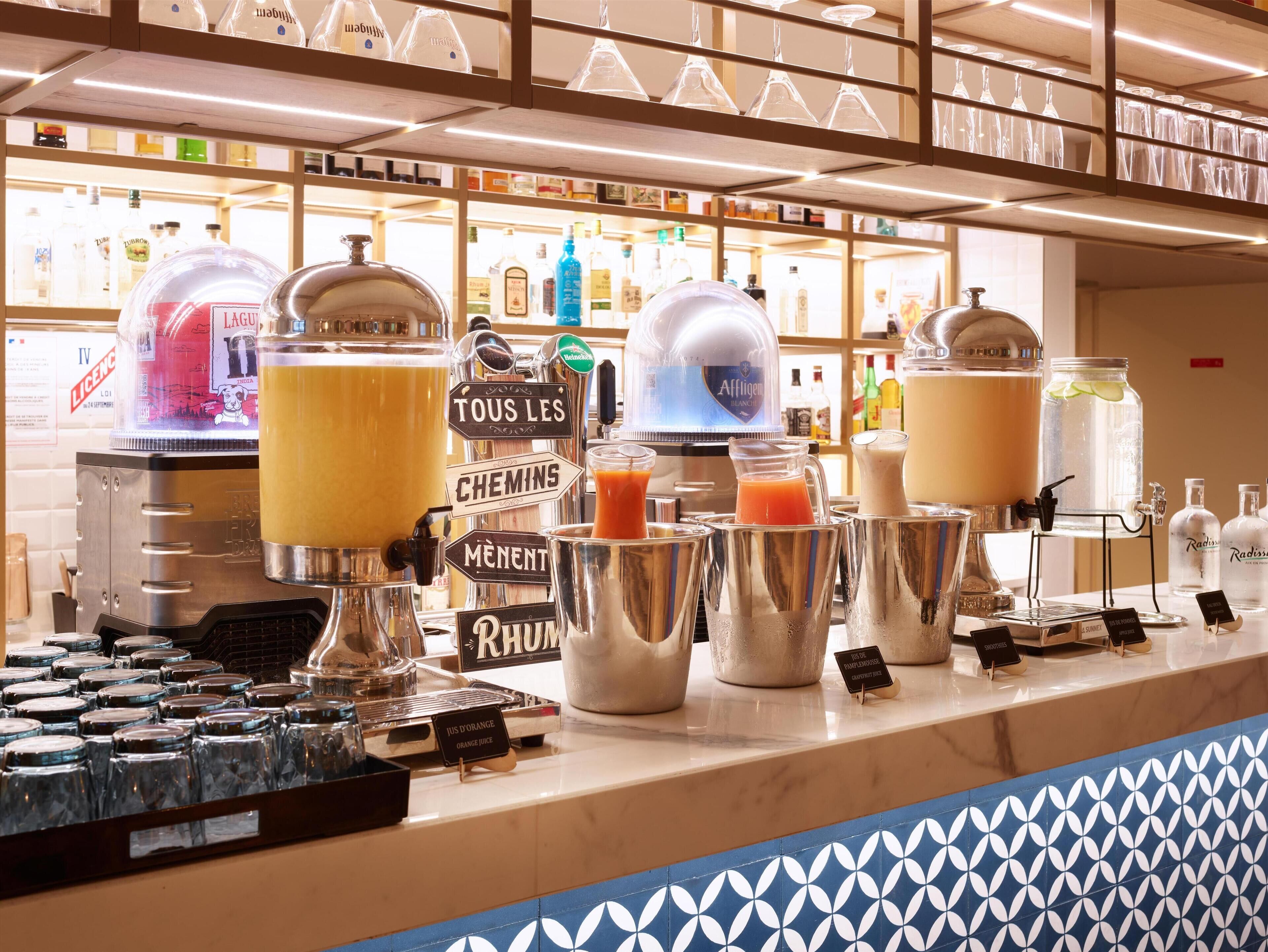Un espace bar doté de plusieurs distributeurs de boissons, d’un assortiment de boissons en bouteille et d’une variété de verres exposés.