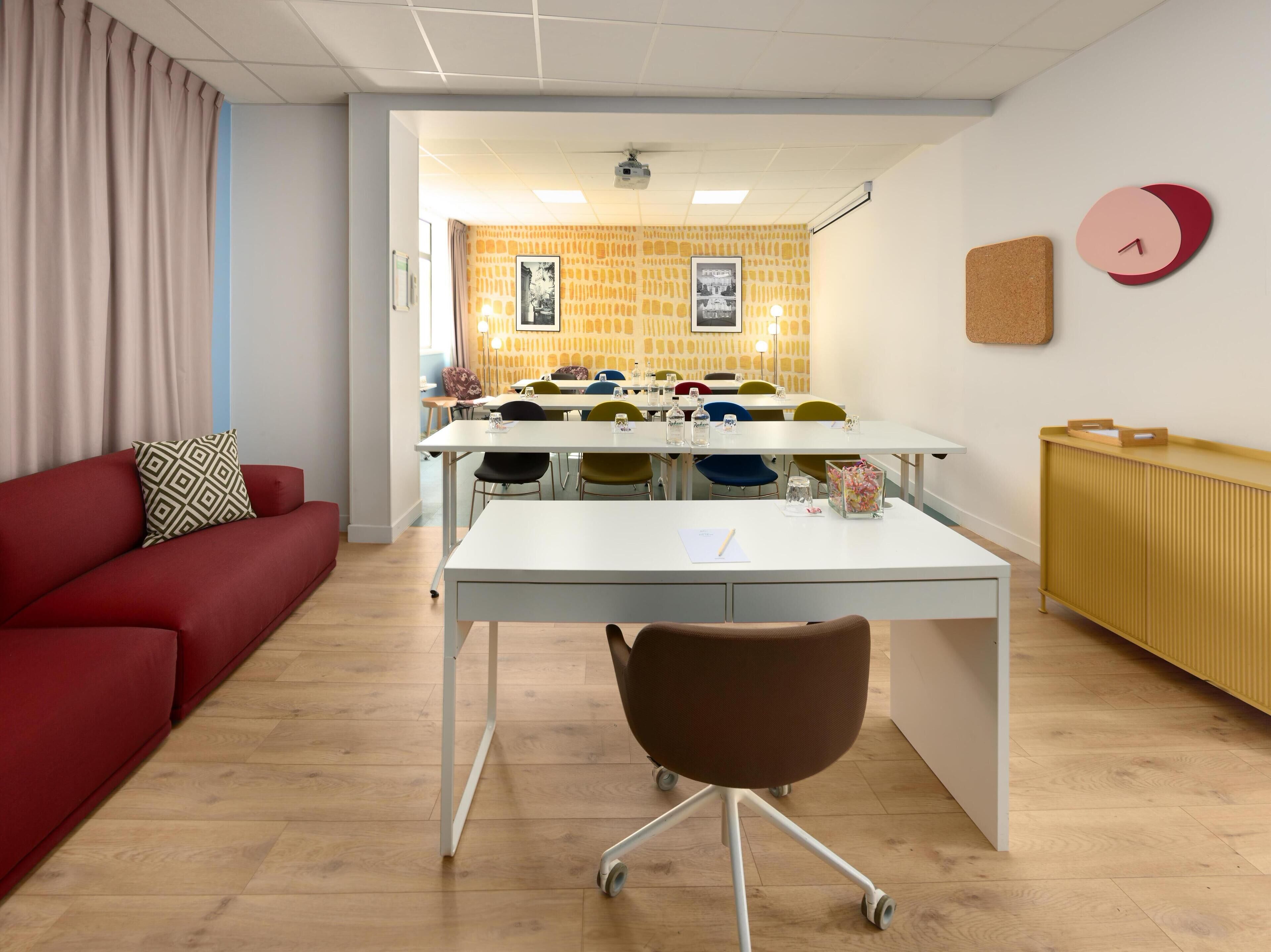 A modern office space with a white desk, a red sofa, and a yellow patterned wall.