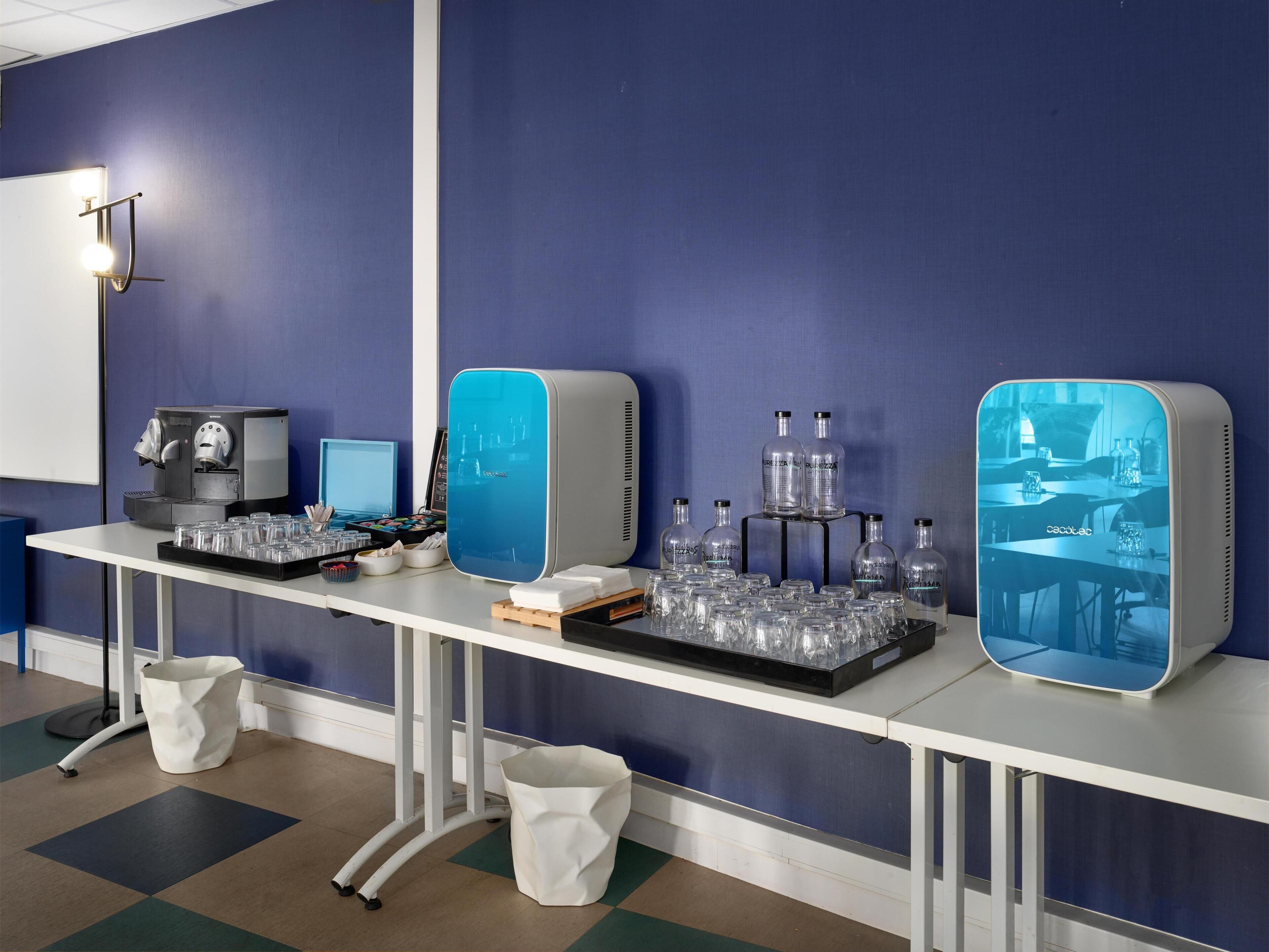 A hotel bar area with multiple beverage dispensers, a computer monitor, and a digital menu display.