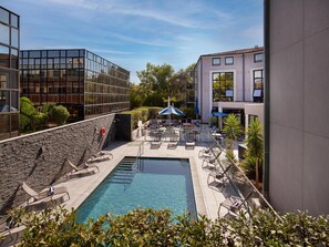 A rooftop pool area with lounge chairs, a clear pool, and a modern building with glass windows. - Radisson Hotel Aix en Provence (Aix-en-Provence)