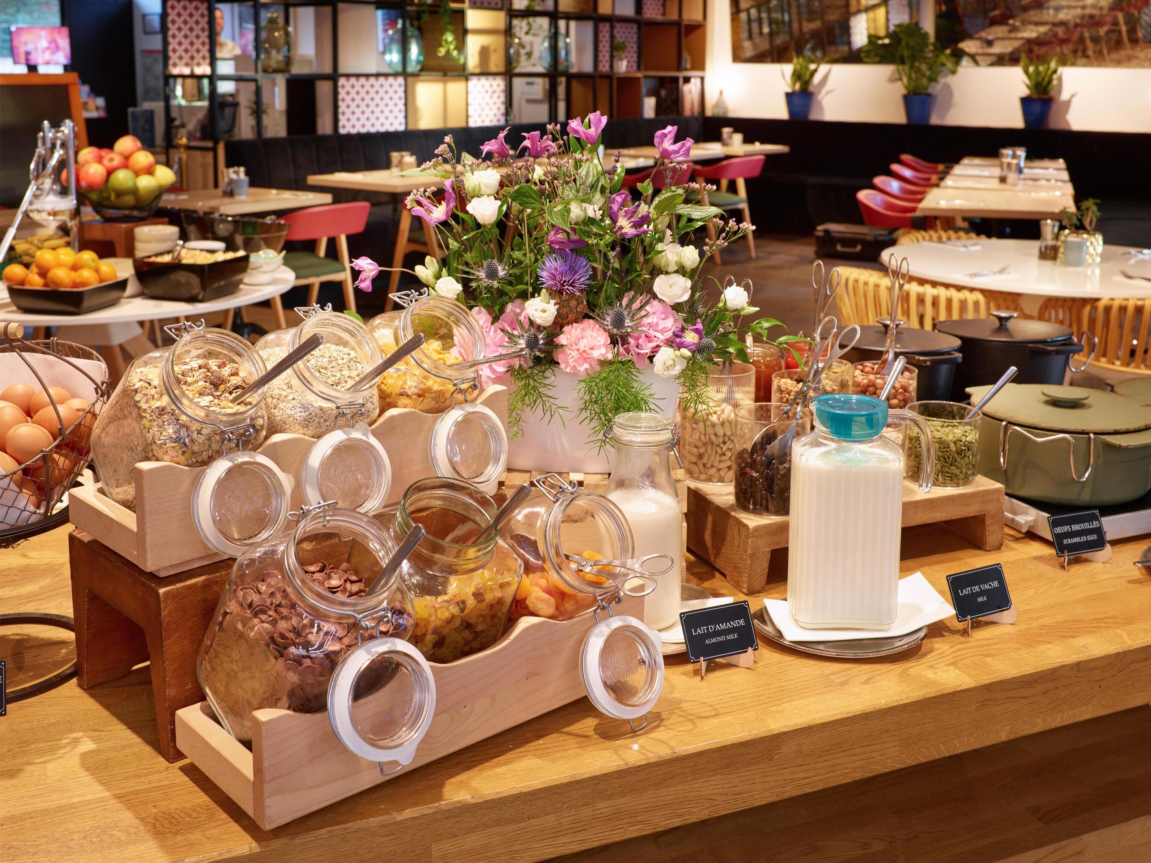 A breakfast buffet with various food items and a floral centerpiece.