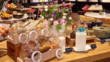 A breakfast buffet with various food items and a floral centerpiece.