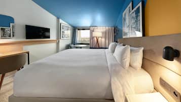 Hotelkamer met een groot bed, een bureau, een stoel, een televisie en een raam met gordijnen.
