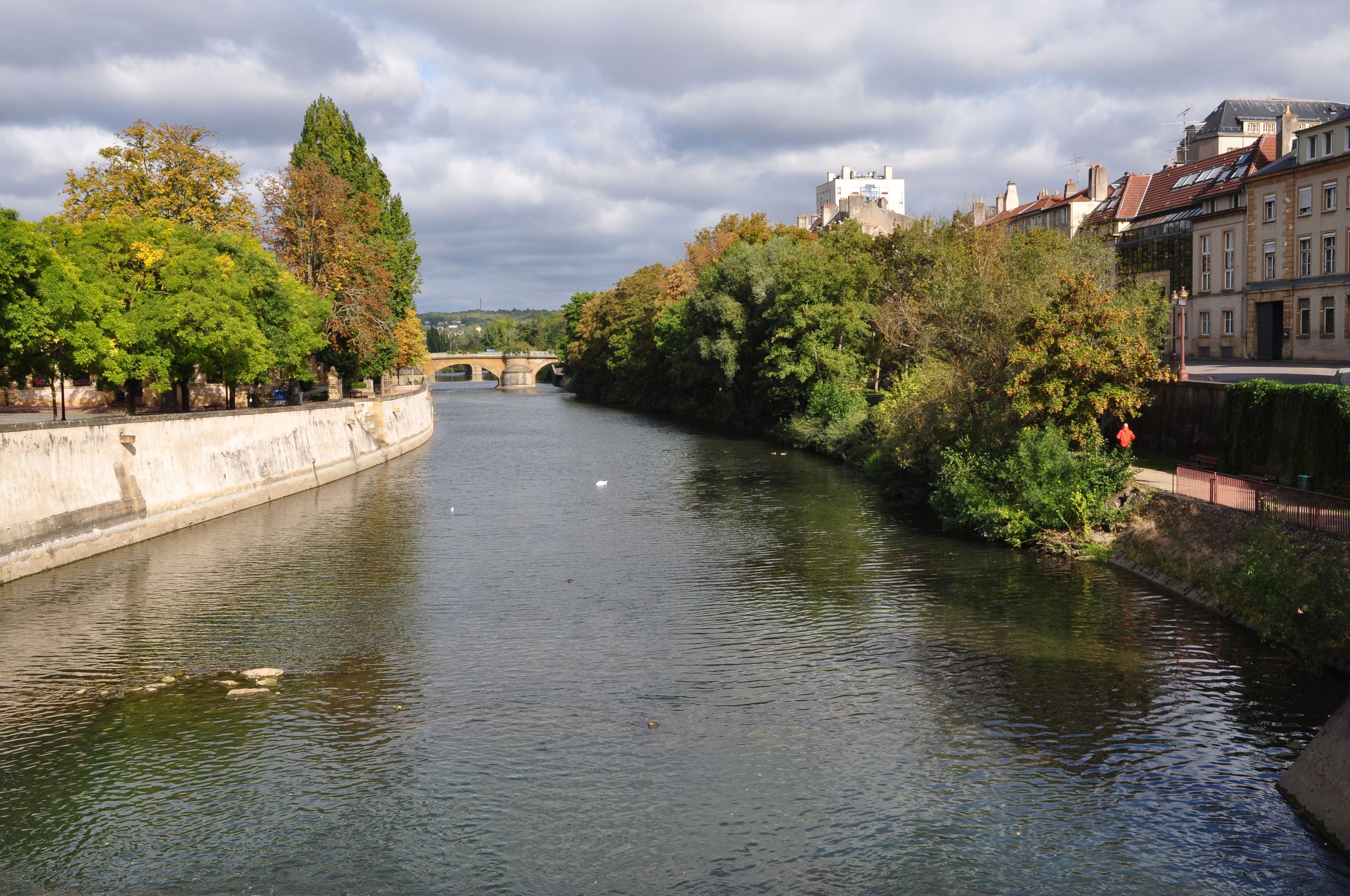 A river with a bridge, trees, and buildings along the banks.