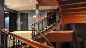 A multi-level interior with a curved staircase, black doors, and a carpeted floor. - ibis Styles Metz Centre Gare (Metz)