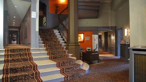 A grand staircase with ornate carpeted steps leading to a second floor. A reception desk is visible in the background. - ibis Styles Metz Centre Gare (Metz)