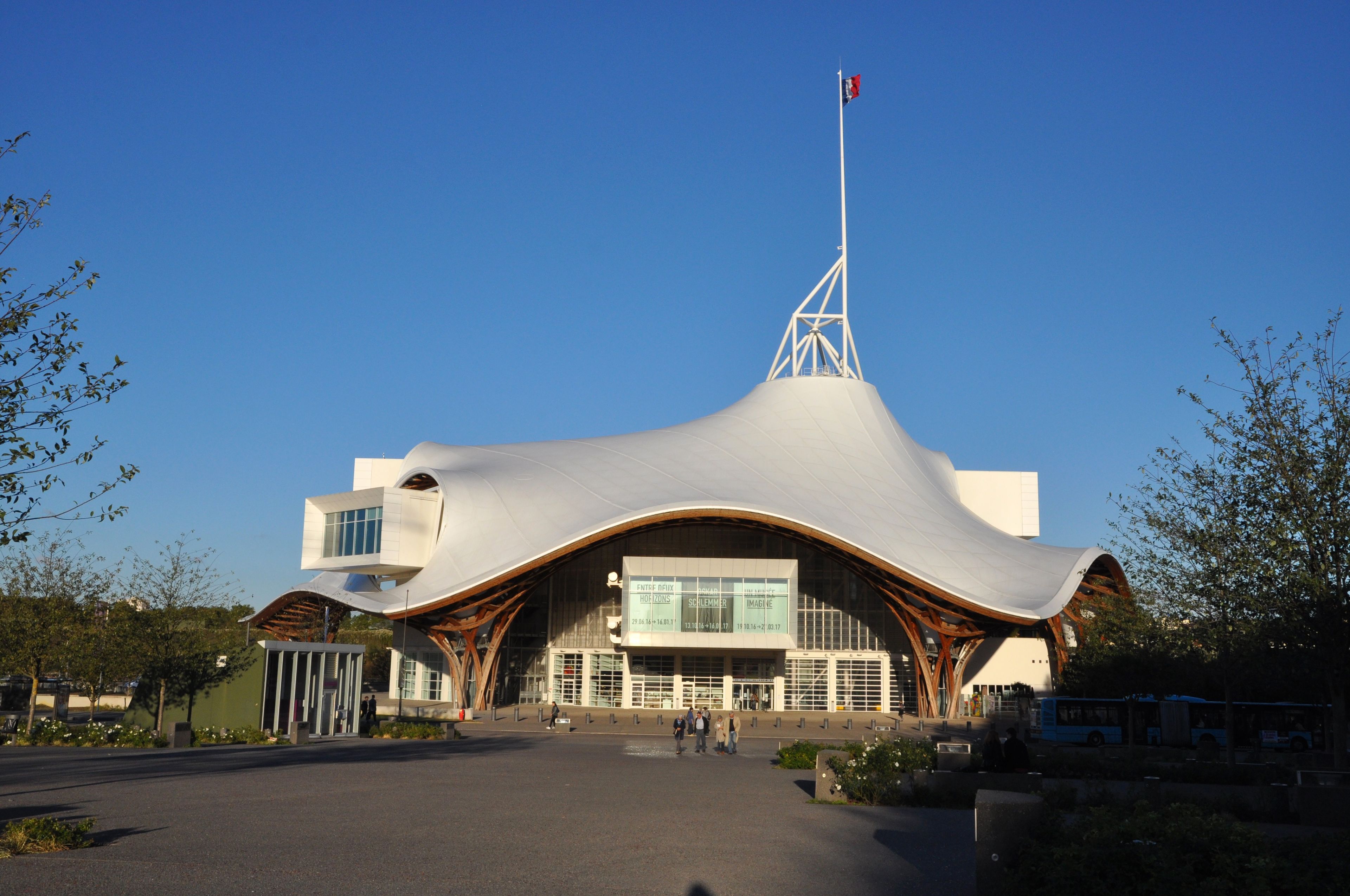 A modern building with a unique, curved roof and a tall flagpole.