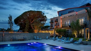 Et moderne hotel med swimmingpool, liggestole og en stenvæg.