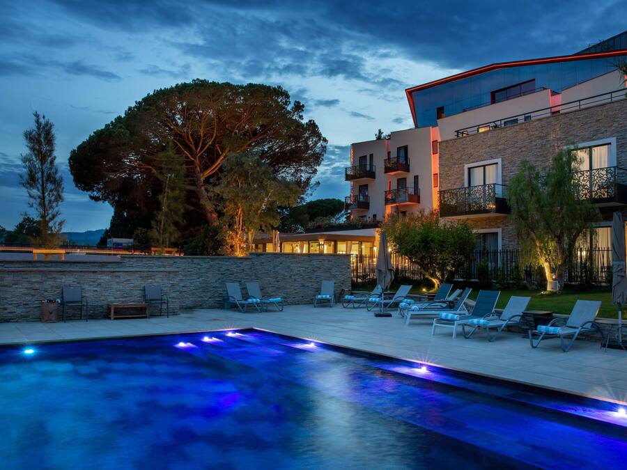 Un hotel moderno con piscina, sillas de descanso y una pared de piedra.