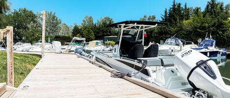 A wooden dock with several boats docked at a marina, surrounded by trees.