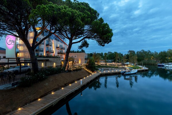 A waterfront hotel with a dock, a large tree, and a calm lake.