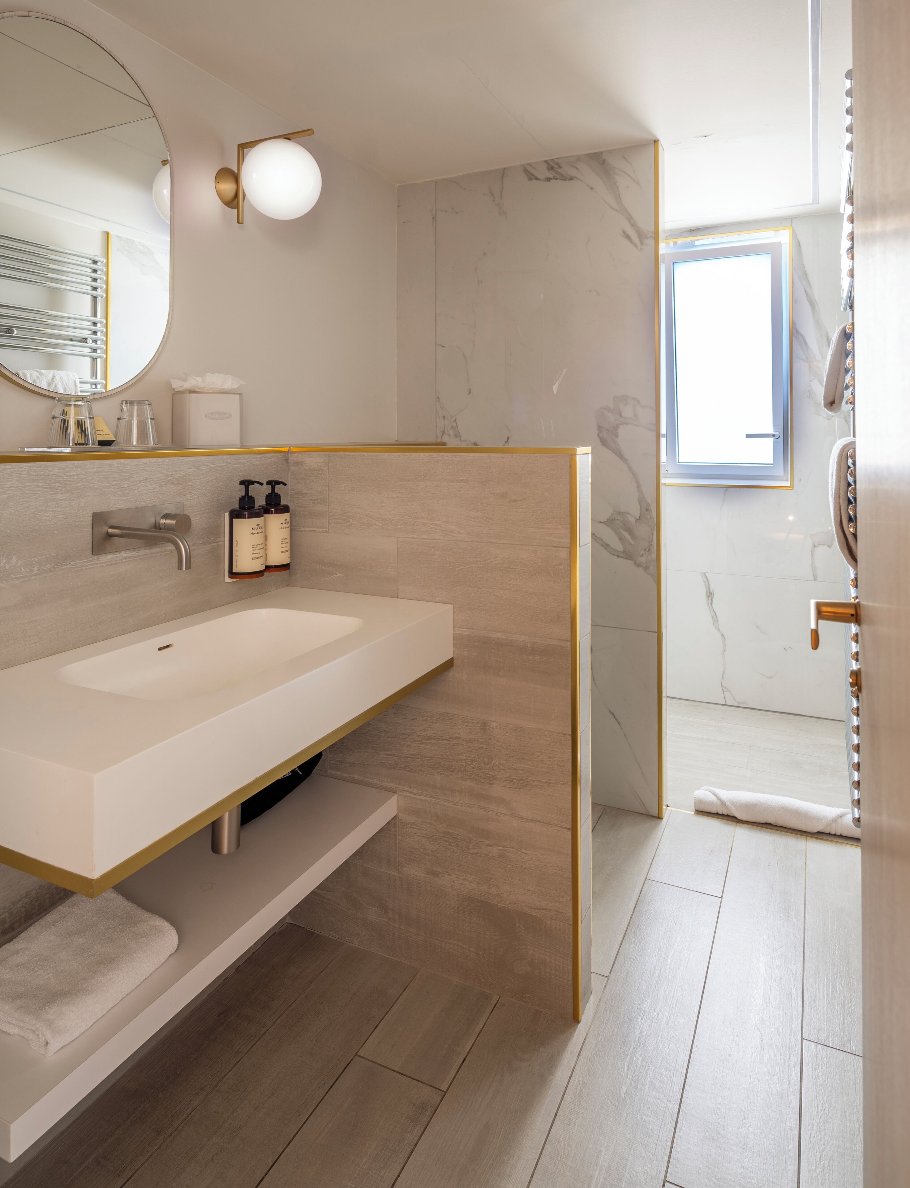 A modern bathroom with a large sink, mirror, and a shower area.
