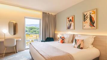 Ein Hotelzimmer mit einem großen Bett, einem Schreibtisch, einem Stuhl und Bildern an den Wänden.