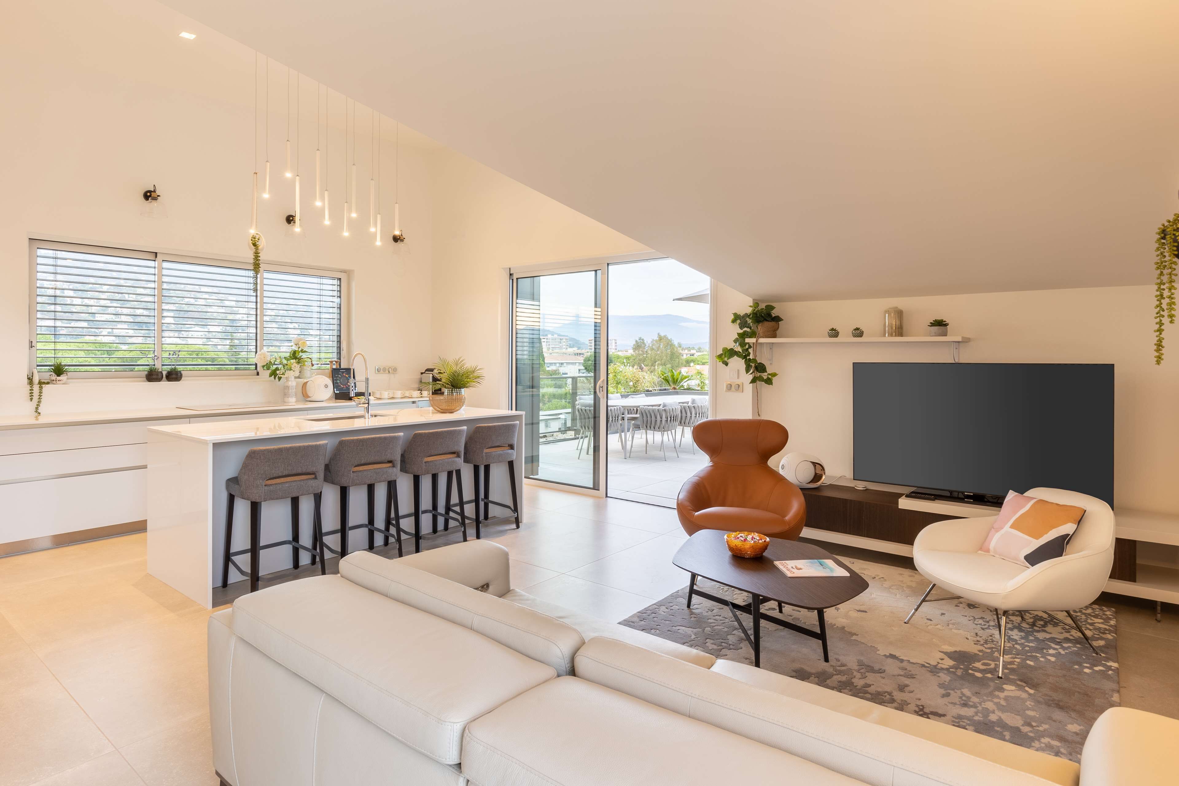 A modern living space with a kitchen, dining area, and a seating area with a TV.