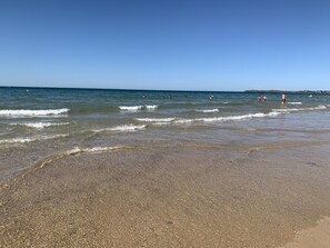 A beach with clear water and a few people swimming. - Hotel Kyriad Saint Malo centre Plage (Saint-Malo)