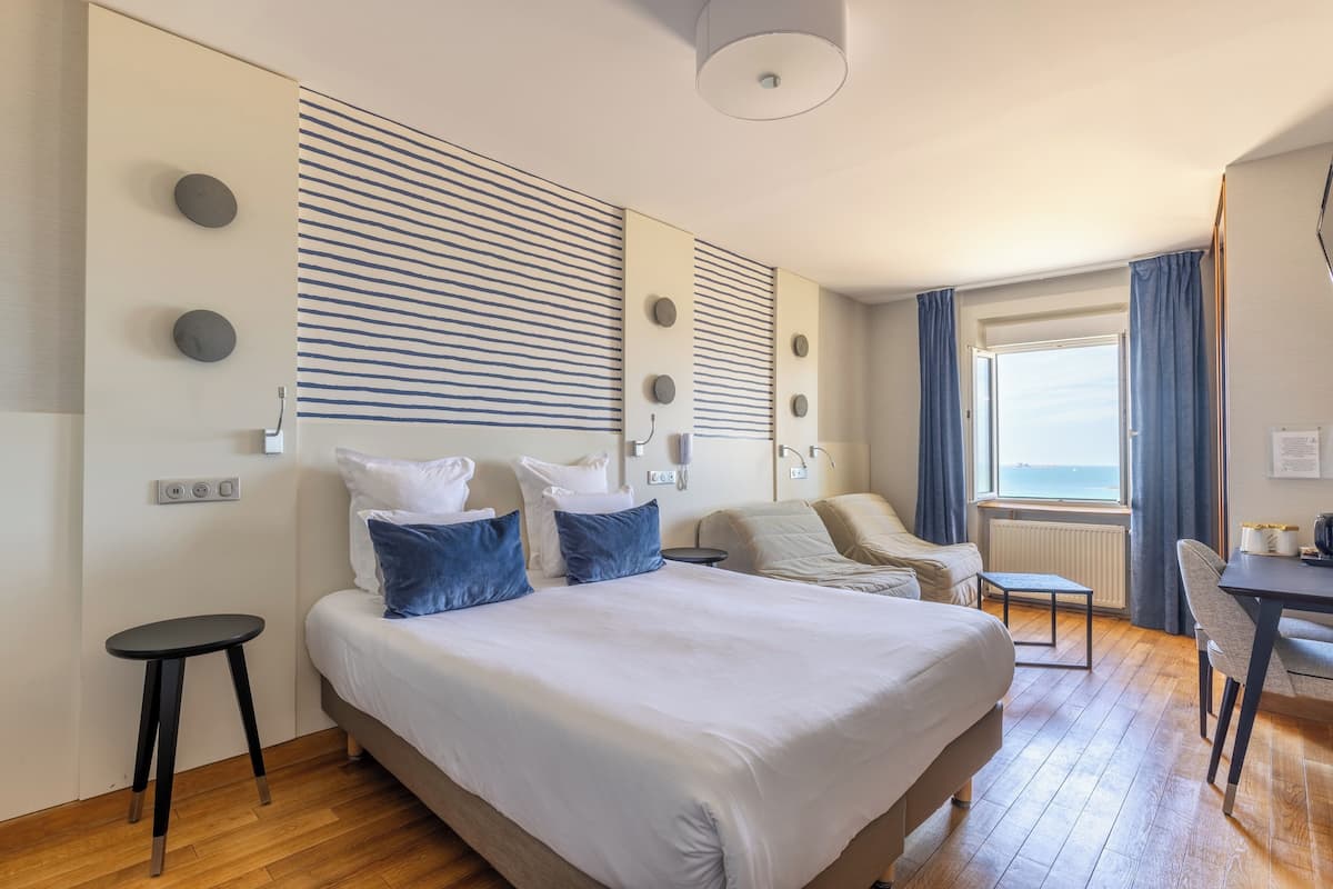Ein modernes Hotelzimmer mit einem großen Bett, einem Schreibtisch und Meerblick.