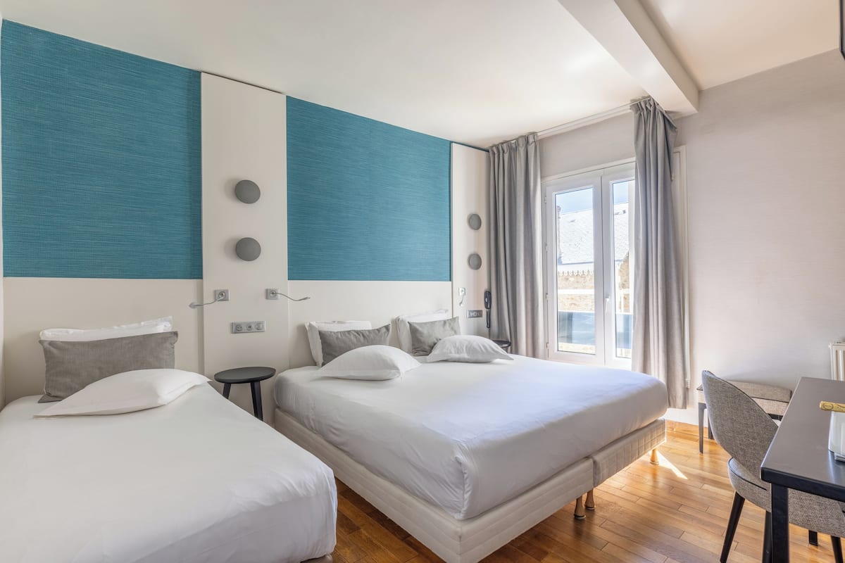 Ein Hotelzimmer mit zwei Betten, einem Schreibtisch und Blick ins Freie.