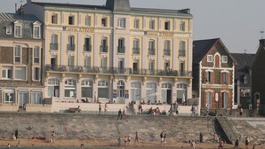 A multi-story hotel with balconies and a beach in the foreground. - Hotel Kyriad Saint Malo centre Plage (Saint-Malo)