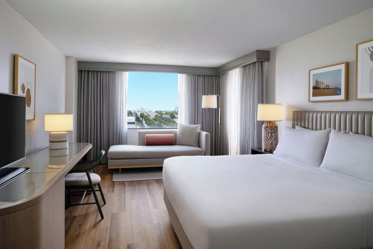 Una habitación de hotel con cama, escritorio, sofá y vistas a la ciudad.