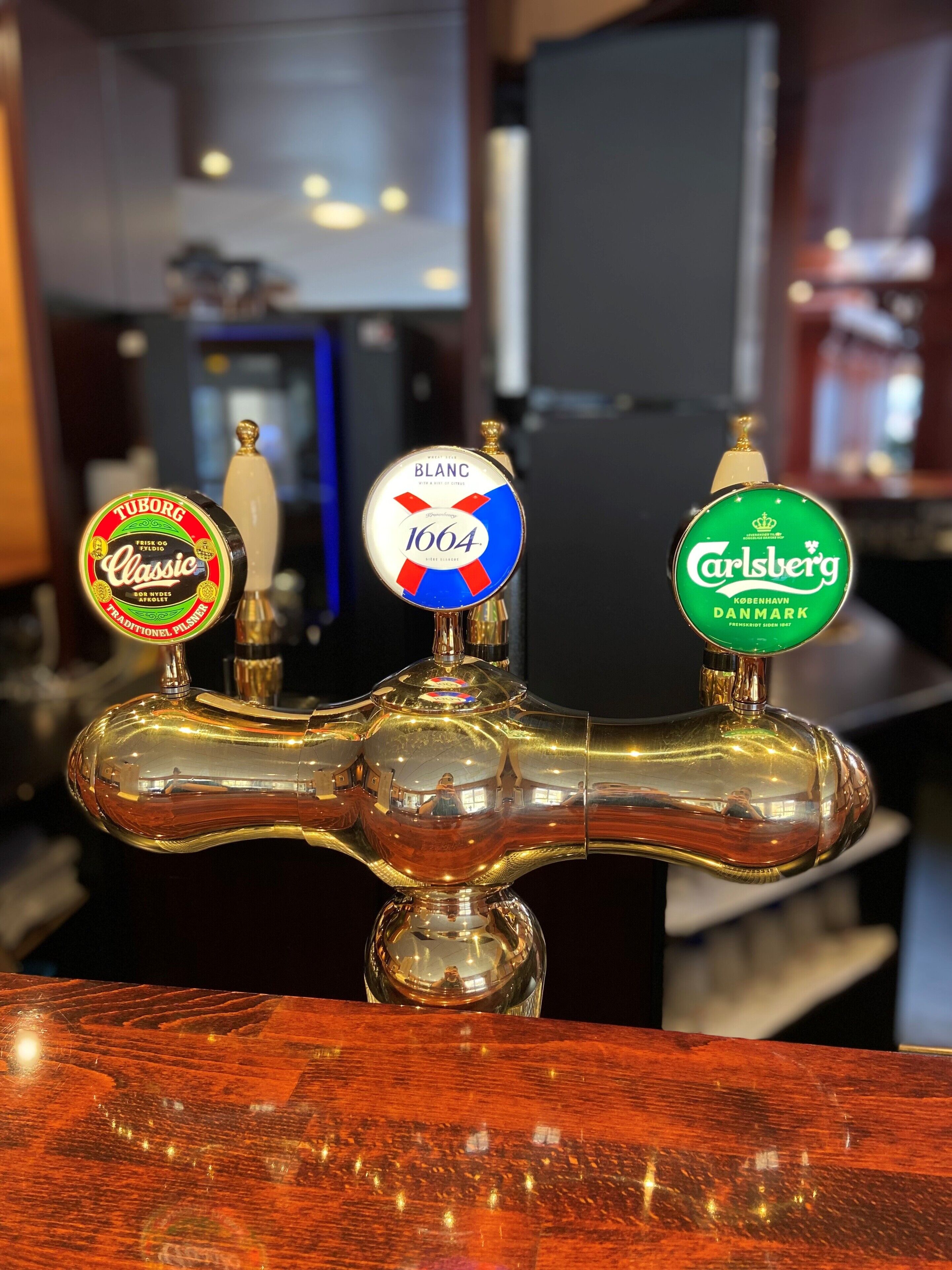 A tap with three beer taps labeled 'Tuborg Classic', 'Blanc 1664', and 'Carlsberg Copenhagen'.