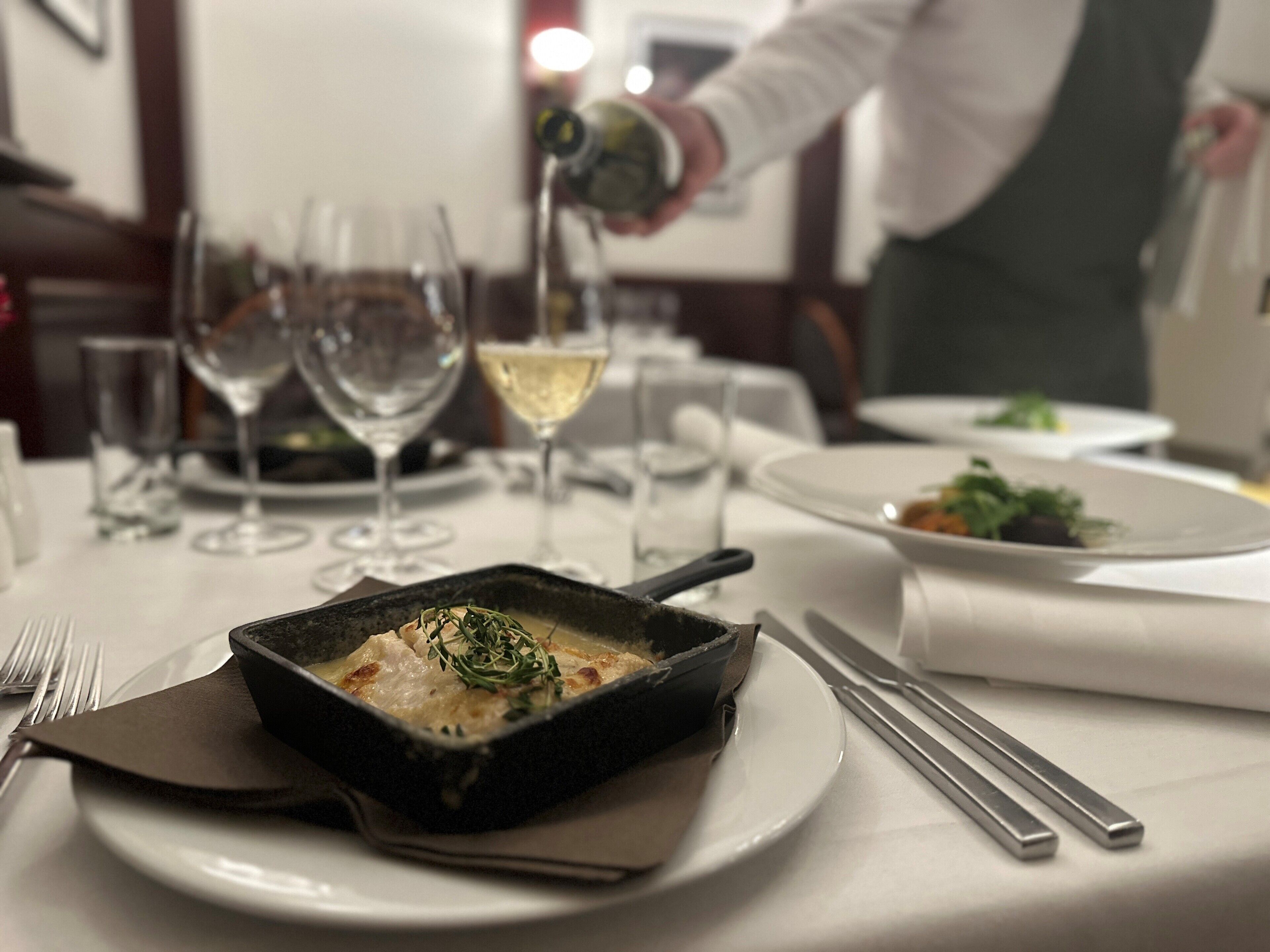 Une table à manger avec un repas, des verres à vin et des couverts.