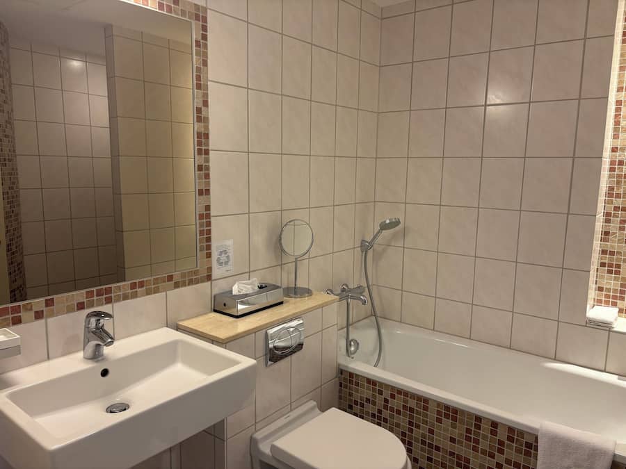 Kylpyhuone, jossa on pesuallas, peili, wc ja kylpyamme.