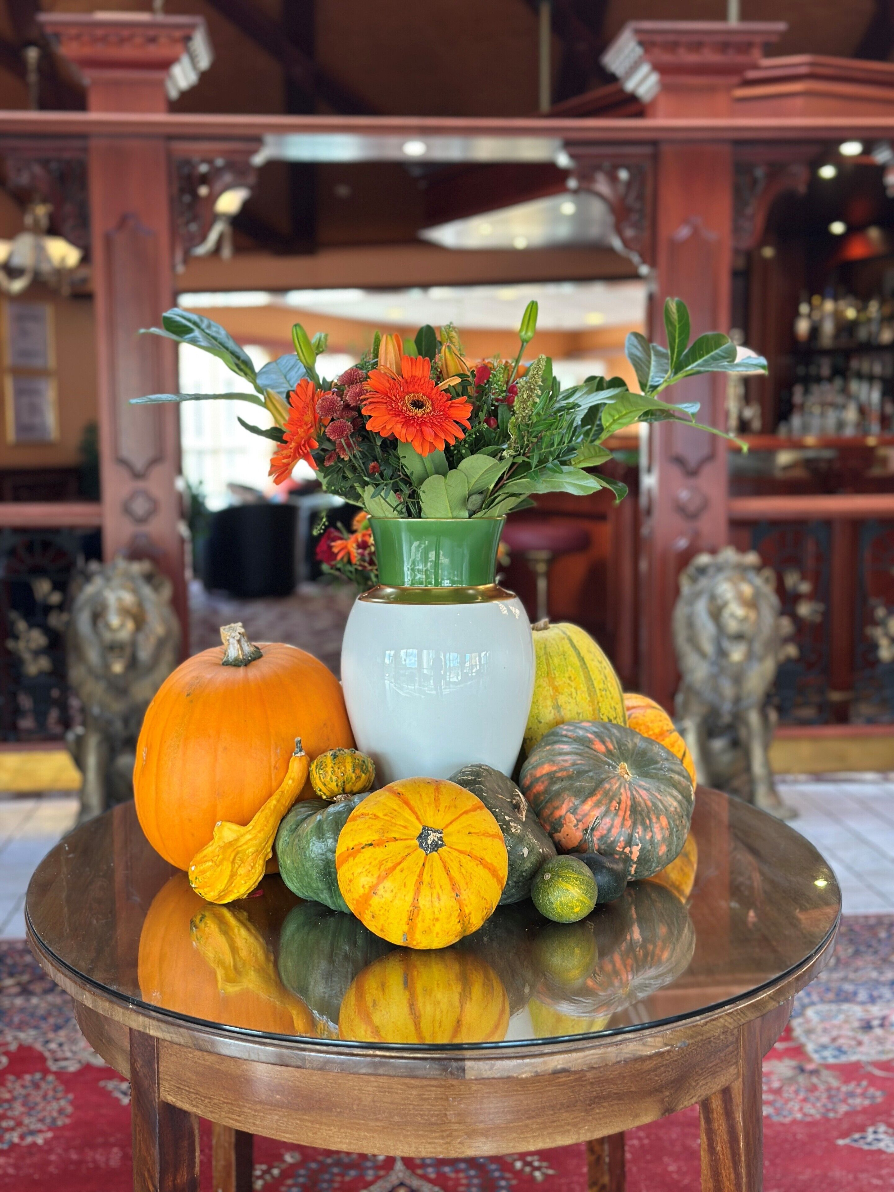 A table with a vase of flowers and various pumpkins.