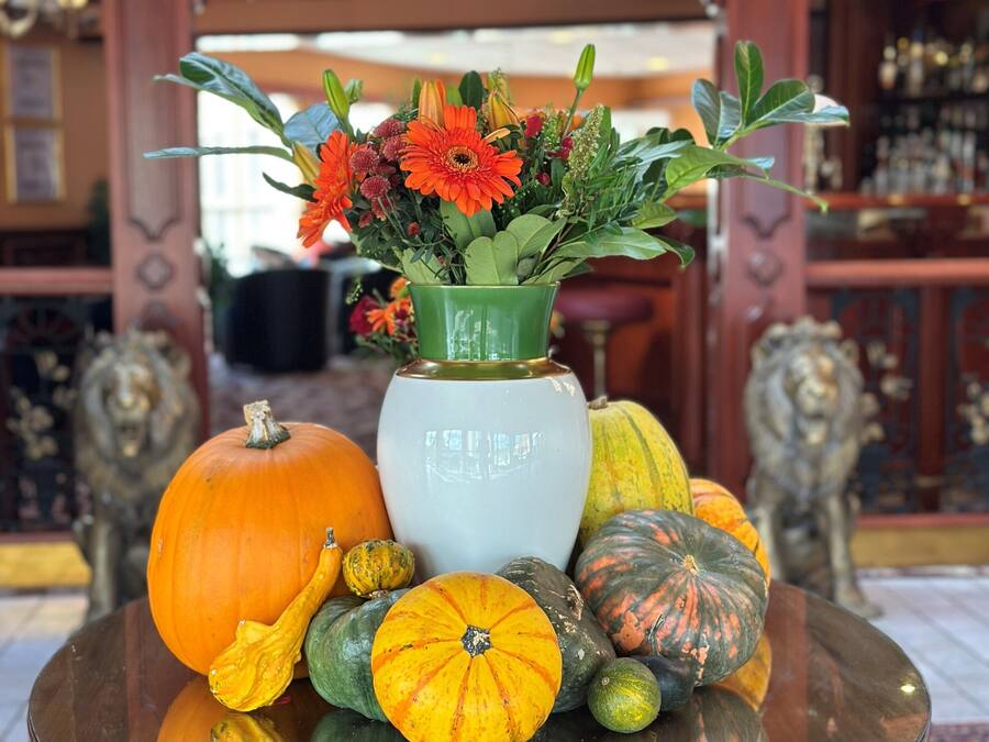 A table with a vase of flowers and various pumpkins.