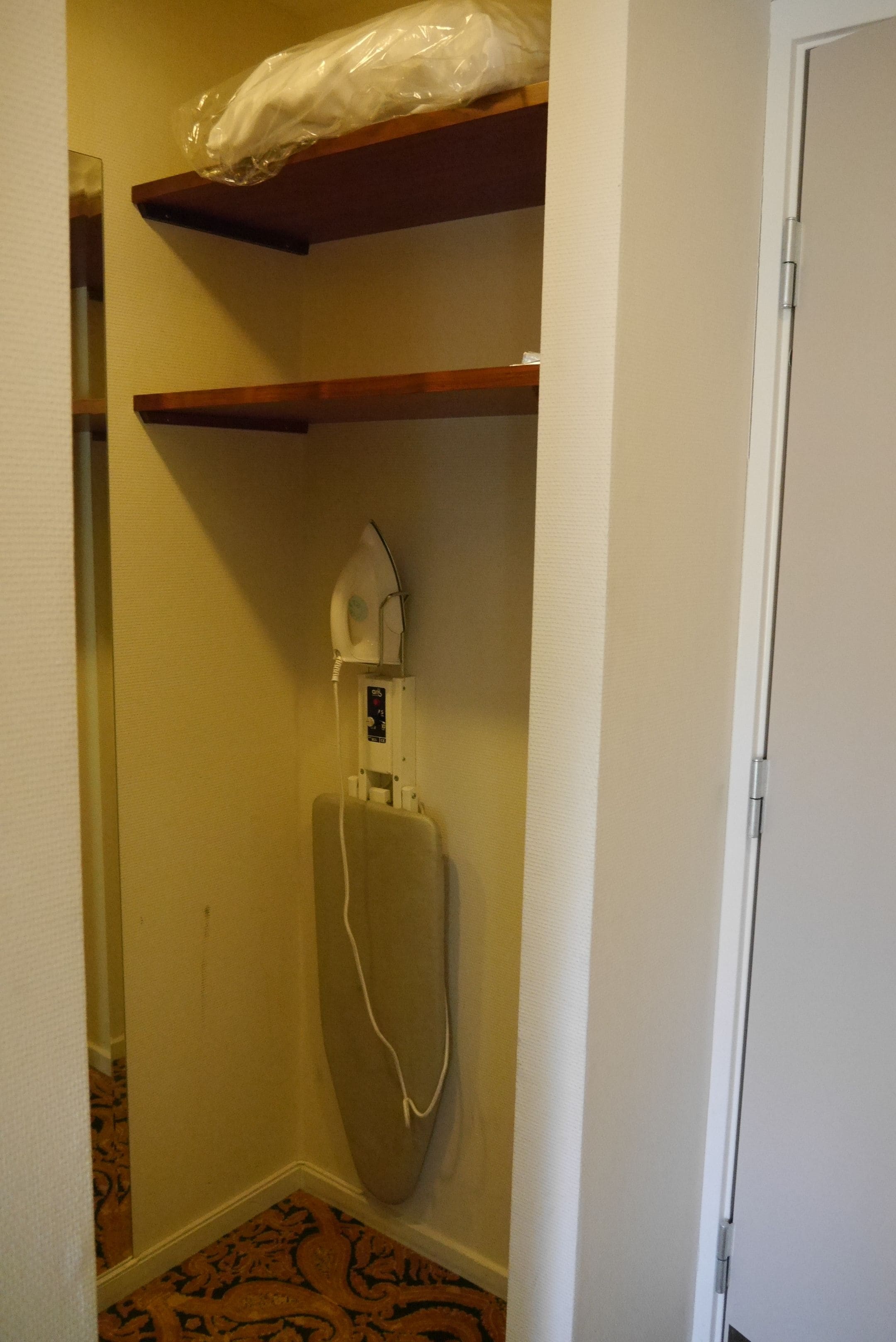 Een hoek van een kamer met een houten plank, een whiteboard en een deur.