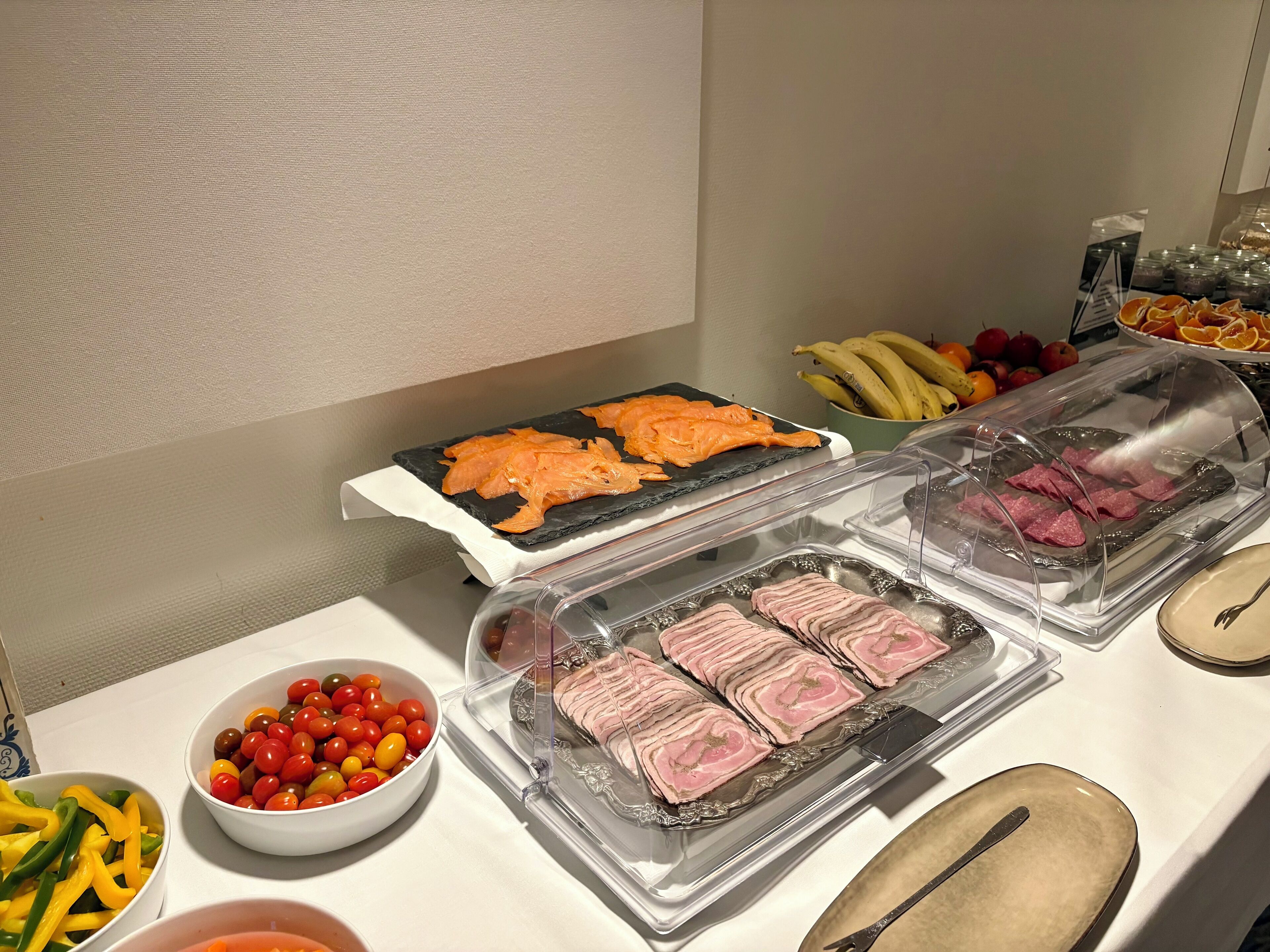 Ein Buffet mit verschiedenen Speisen, darunter Lachs, Schinken und Kirschtomaten.