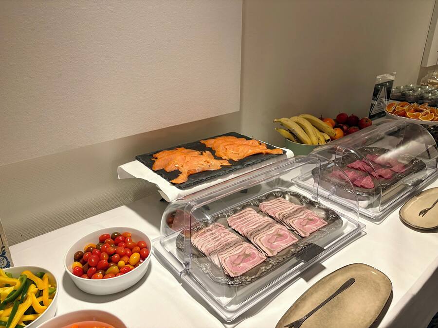 Ein Buffet mit verschiedenen Speisen, darunter Lachs, Schinken und Kirschtomaten.