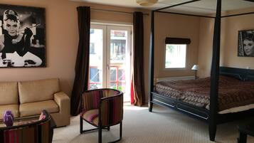 Una camera da letto con un letto a baldacchino, un divano, una poltrona a righe e un'ampia finestra con tende.