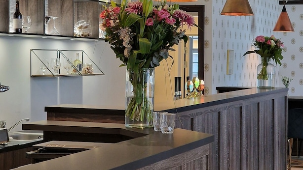 A reception area with a wooden reception desk, a vase of flowers, and a mirror above the desk.