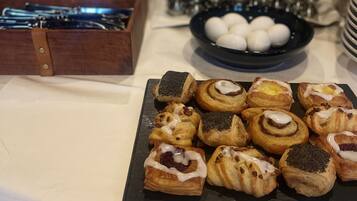 A buffet table with various pastries and a black plate of white eggs.