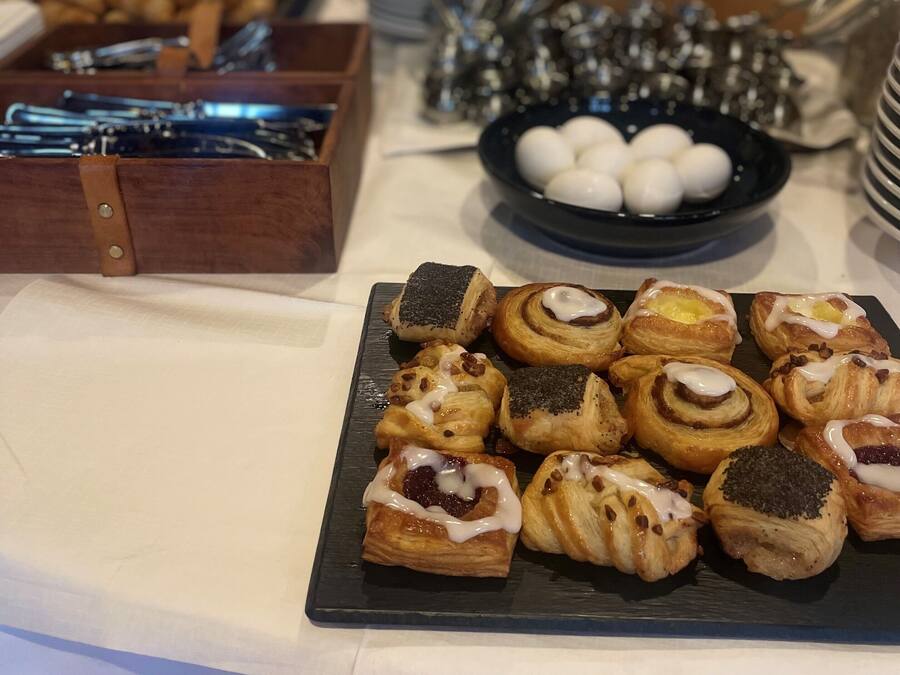 A buffet table with various pastries and a black plate of white eggs.