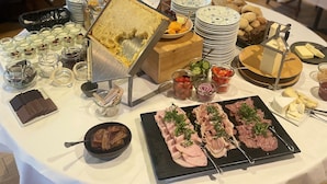 A buffet table with various food items, including a cake, meats, cheeses, and fruits.