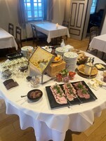 En buffetbord med forskellige retter, blandt andet kage, kød, oste og frugt.