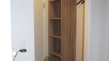 A room with a wooden desk, a chair, and a closet with multiple shelves.