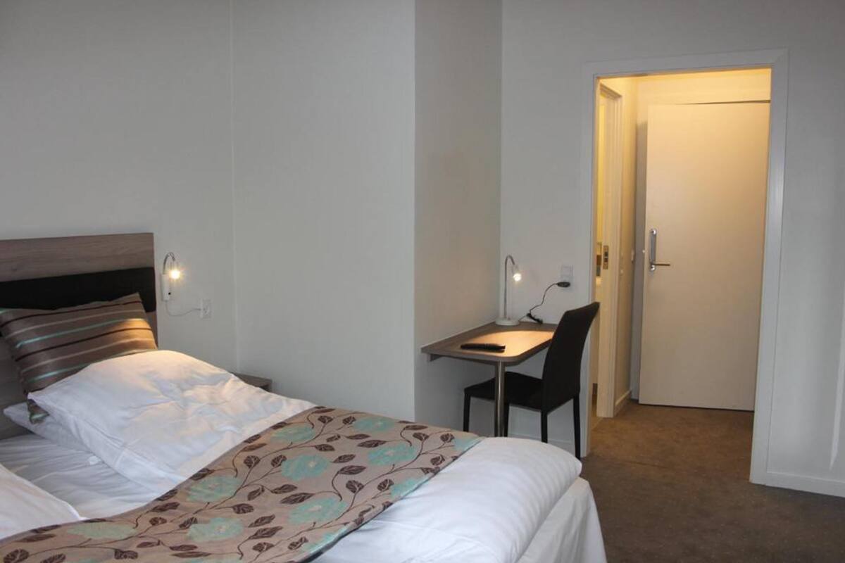 Une chambre d’hôtel avec un lit, un bureau et une chaise, et une porte.