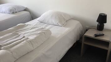 Une chambre d’hôtel avec deux lits, une table de chevet avec une lampe et un tableau au mur.