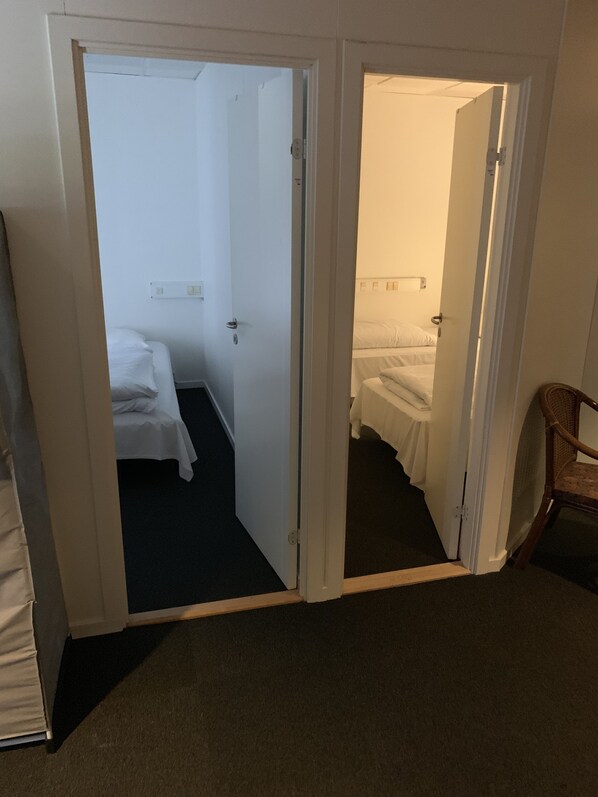 A hotel room with a bed, a chair, and a door leading to another room.