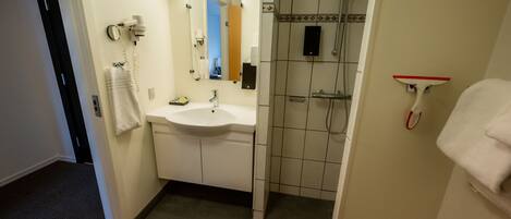 Une salle de bain équipée d’un lavabo, d’un miroir, d’un porte-serviettes et d’une douche.