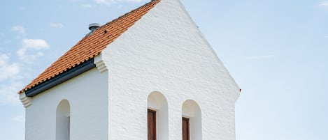 A white church with a cross on top, a red-tiled roof, and the year 1869 on its facade.