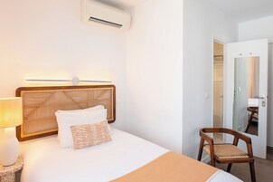 A hotel room with a bed, a bedside lamp, a chair, and a mirror.