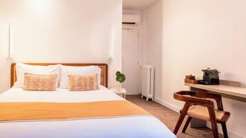 Ein Hotelzimmer mit einem Bett, einem Schreibtisch, einem Sessel, einem Heizkörper und einer kleinen Pflanze.