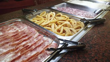 A buffet with various food items including bacon, pasta, and rice.