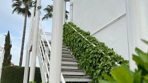 Un escalier avec des rampes blanches et un feuillage verdoyant.