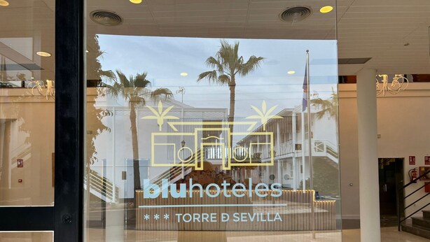 Een hotelentree met een glazen gevel, een logo en de naam 'Bluhoteles' duidelijk zichtbaar.