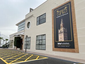 La façana d'un hotel amb un gran cartell publicitari que anuncia 'bluhotel.es' i 'TORRE D SEVILLA'.