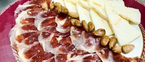 A plate of sliced cured meat and cheese with almonds.